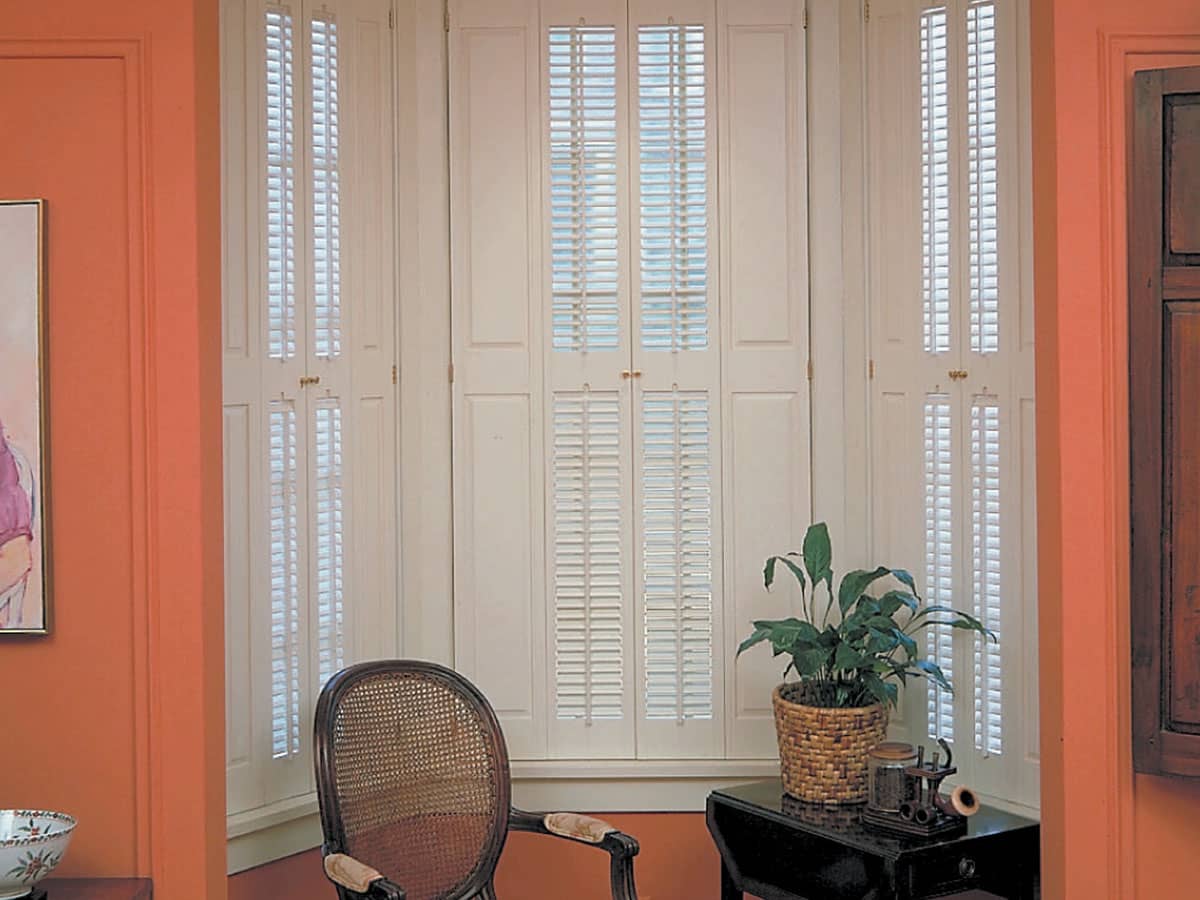 Installed single hung Brownstone shutters with raised panels and traditional louvered leafs Americana DeVenco Shutters